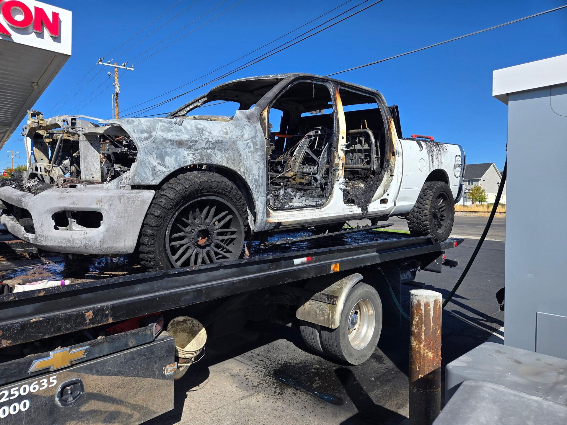 Burned white pickup on a flatbed tow truck
